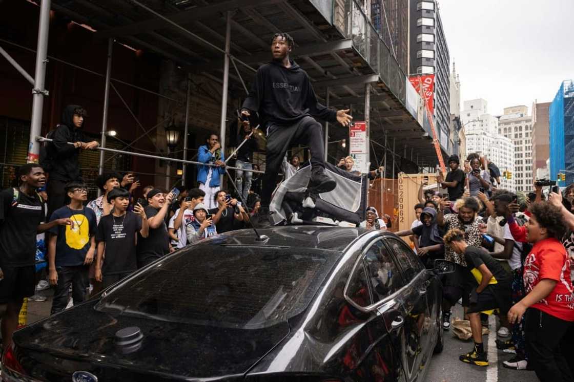 A person jumps on a car during riots sparked by Twitch streamer Kai Cenat, who announced a "givaway" event, in New York's Union Square on August 4, 2023