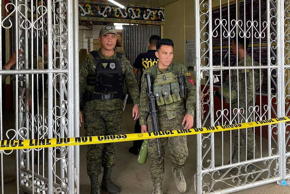 Military personnel stand guard at the entrance of a gymnasium