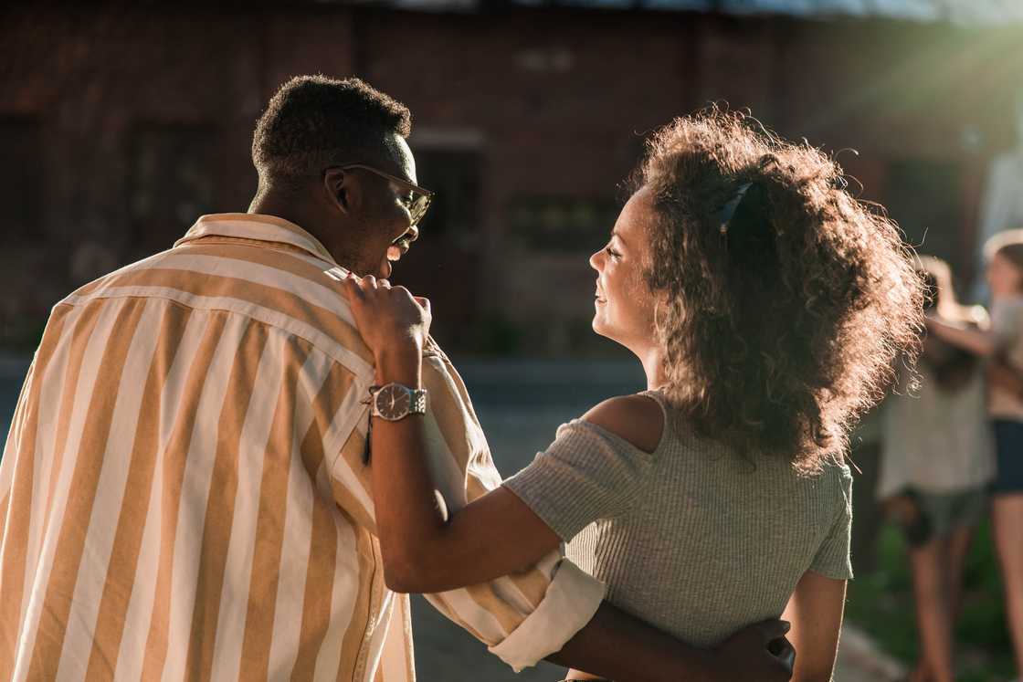 Back view of a happy couple talking in the street.