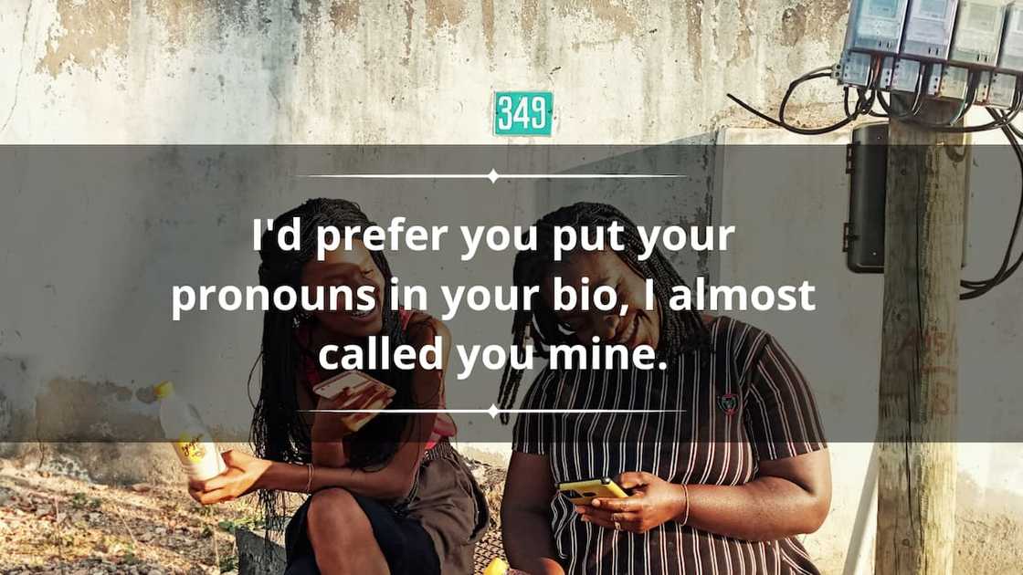 Two women sitting on a stone curb laughing at something on the phone Two women sitting on a stone curb laughing at something on the phone