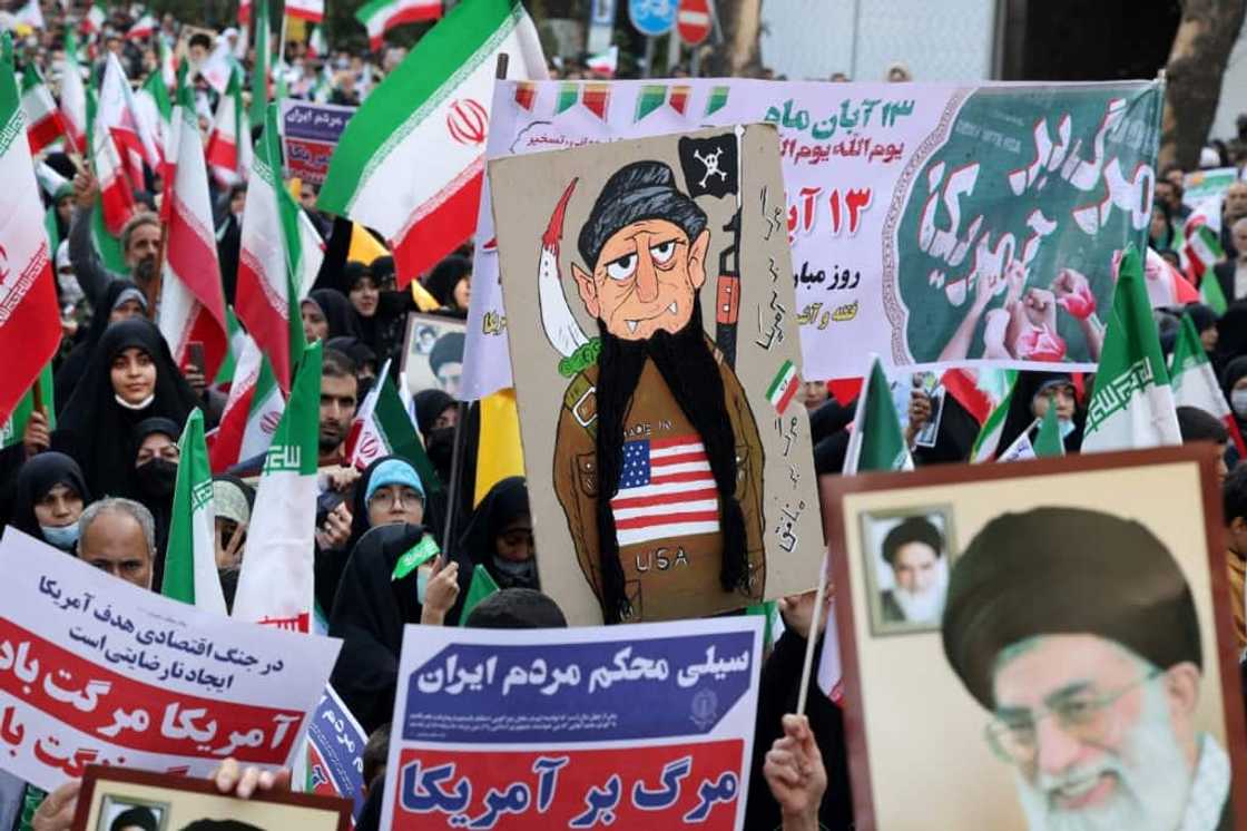 Iranians wave their country's national flag at a rally outside the former US embassy in Tehran