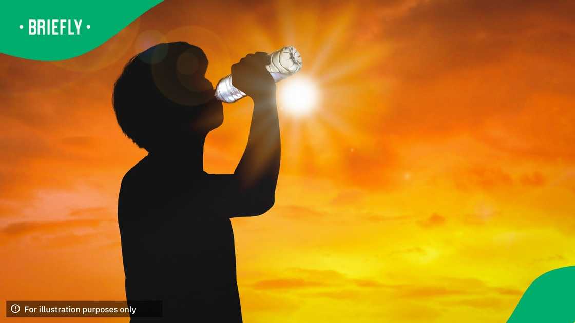 Silhouette man is drinking water bottle on hot weather background with summer season. High temperature and heat wave concept