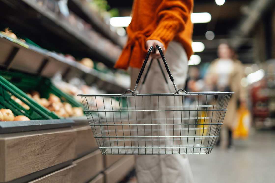 Lower section of young woman standing next to product aisle and choosing vegetables in the store. Lower section of young woman standing next to product aisle and choosing vegetables in the store.