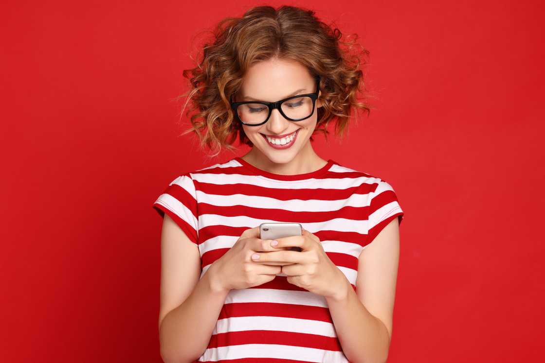 A woman smiling at her phone.