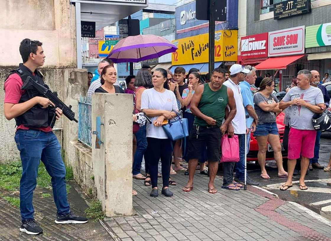 A police officer stands guard as locals gather outside the police station where the perpetrator of two school shootings is being held in Aracruz, Espirito Santo State, Brazil, on November 25, 2022 A police officer stands guard as locals gather outside the police station where the perpetrator of two school shootings is being held in Aracruz, Espirito Santo State, Brazil, on November 25, 2022
