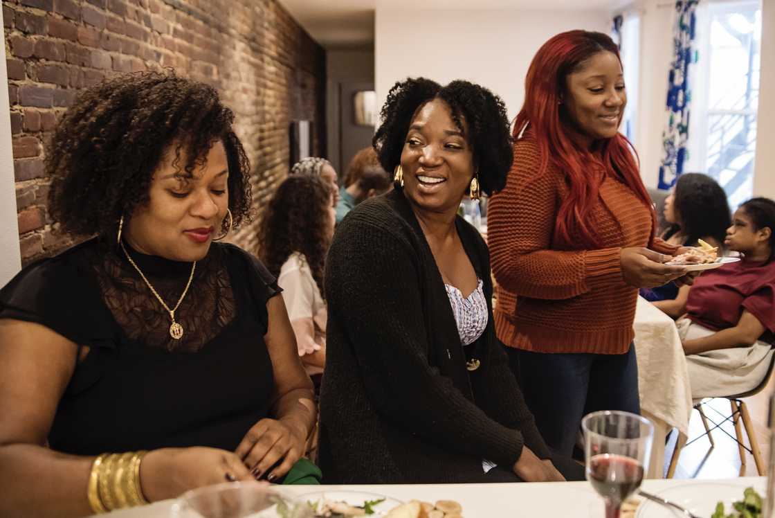 Brunch table with several women laughing while one woman forces a small smile. Brunch table with several women laughing while one woman forces a small smile.