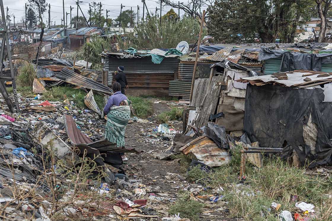 A resident awaits for help with her child as residents rebuild their shacks after a fire destroyed more than 500 structures at the Jika Joe informal settlement in Pietermaritzburg, KwaZulu-Natal, August 11, 2026
