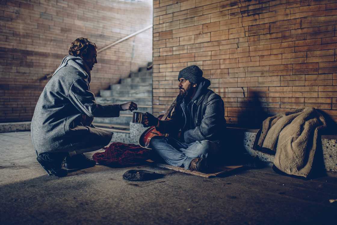 A stock image of a woman helping a beggar