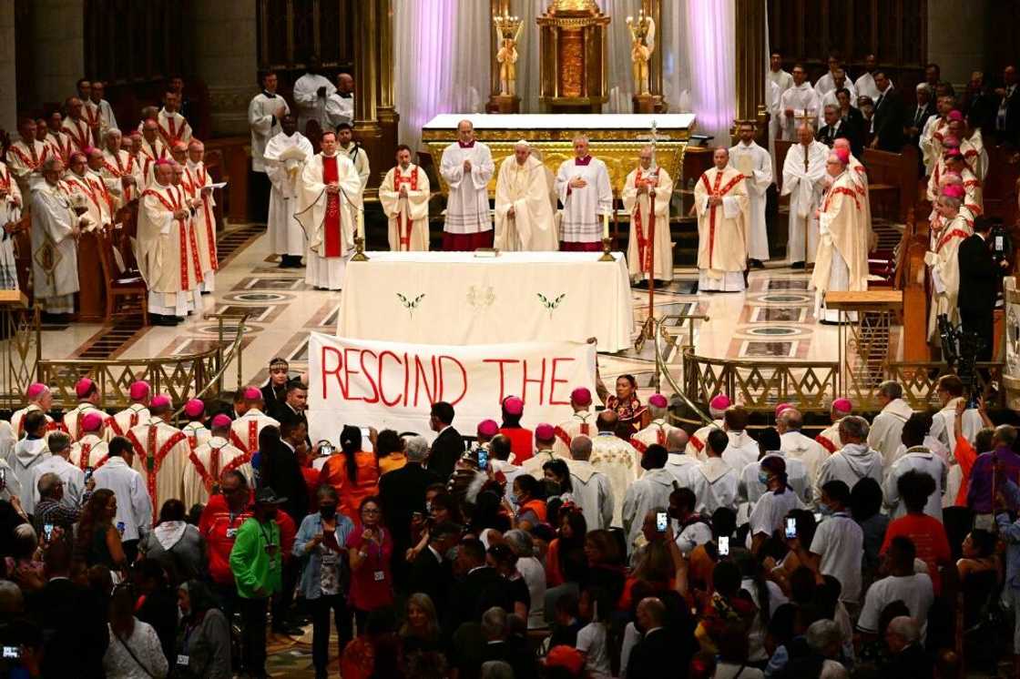 Indigenous people hold a protest banner as Pope Francis celebrates mass at the shrine of Sainte-Anne-de-Beaupre in Quebec, Canada, on July 28, 2022