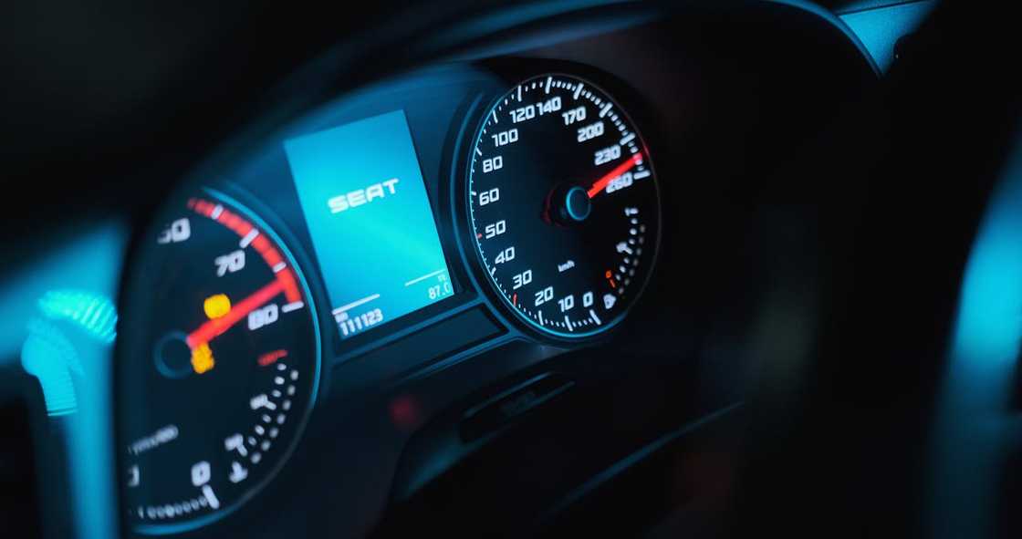 A car dashboard shows a speedometer illuminated in the dark. A car dashboard shows a speedometer illuminated in the dark.