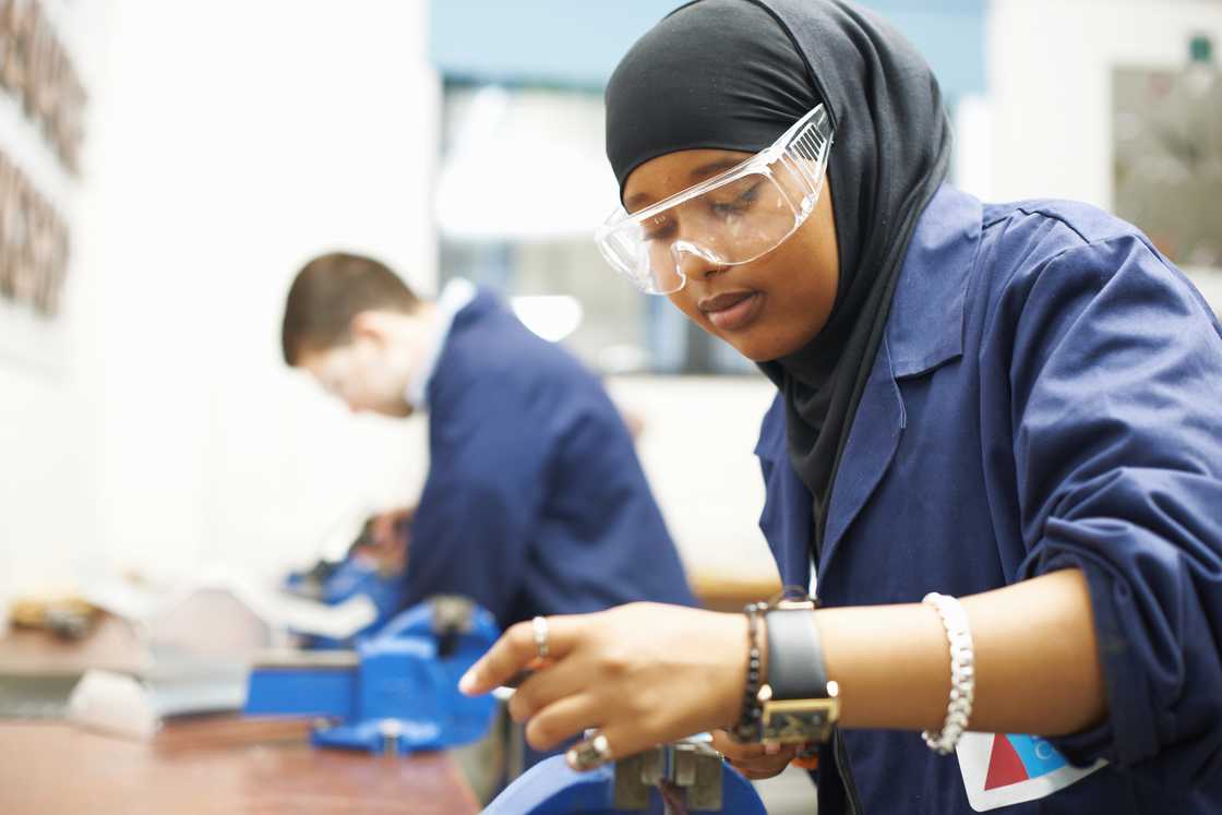 Female student using vice grip in college workshop