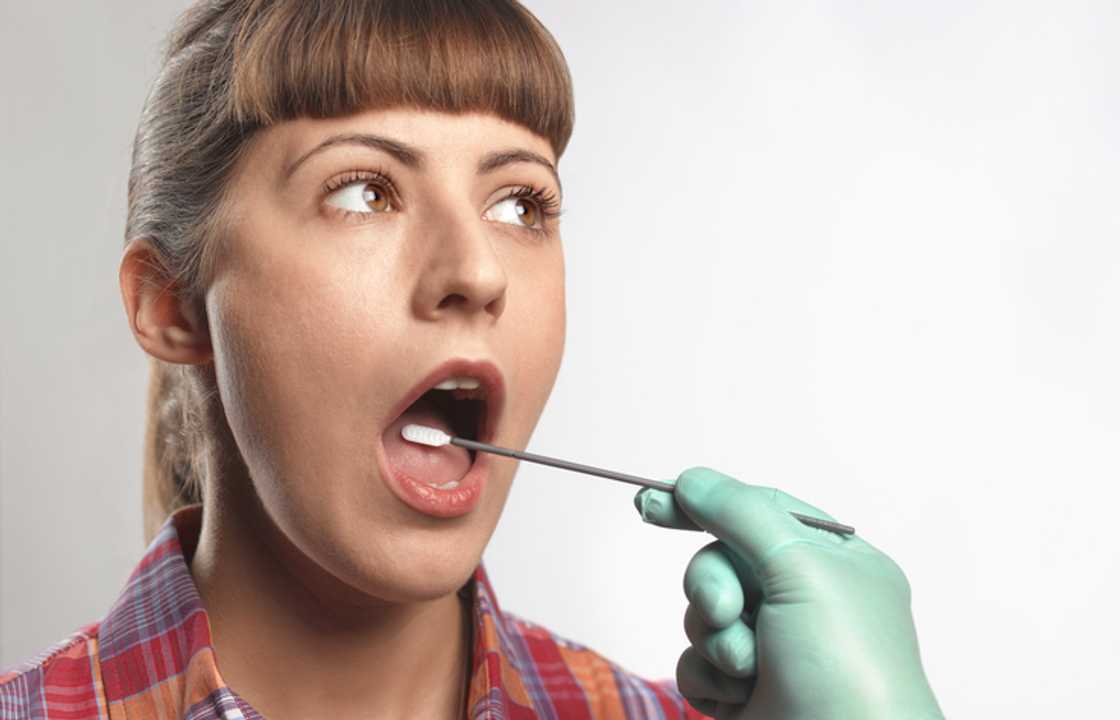 A person inserting a DNA test swab into a woman’s mouth.