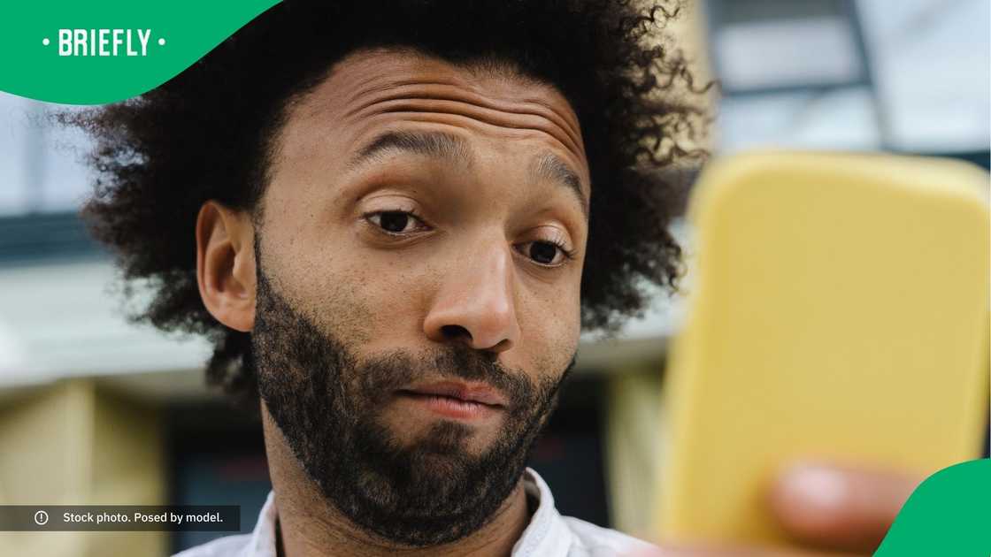 A man with raised eyebrows using his smart phone. A man with raised eyebrows using his smart phone.