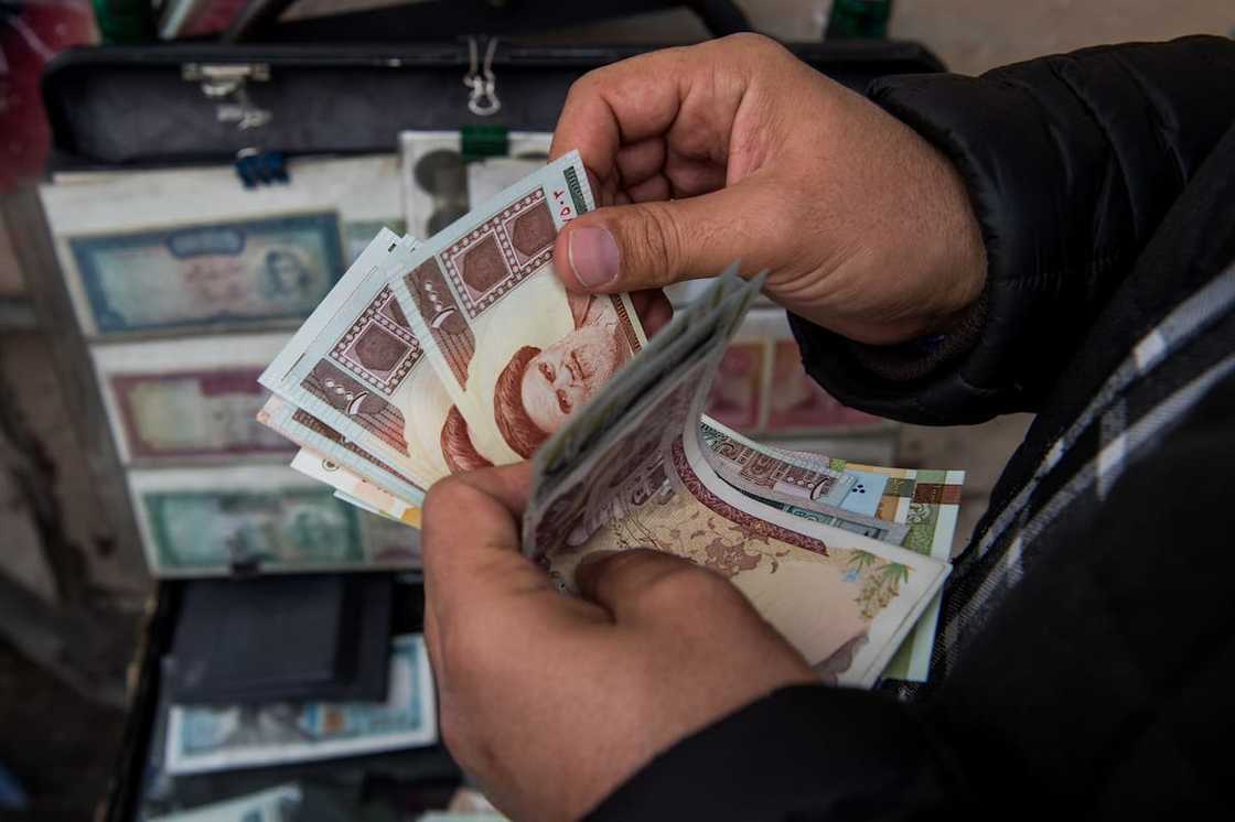 A currency trader counts Iranian rial banknotes at a money exchange market A currency trader counts Iranian rial banknotes at a money exchange market