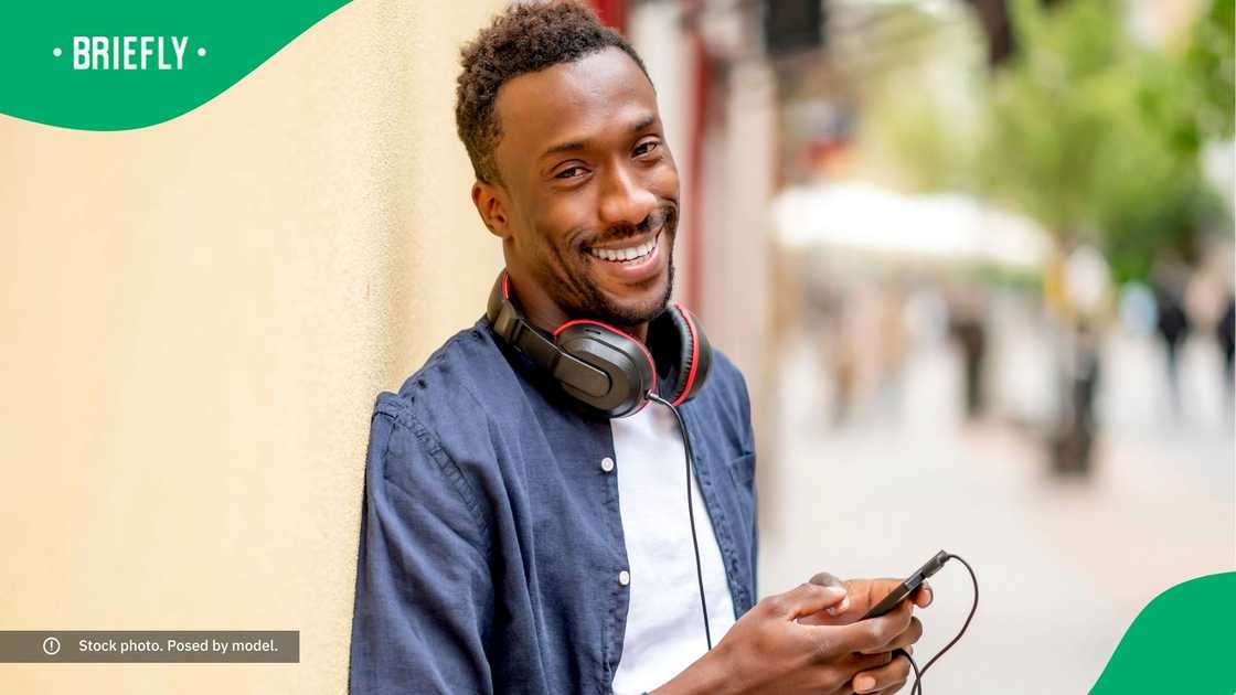 A smiling man holding his phone. A smiling man holding his phone.