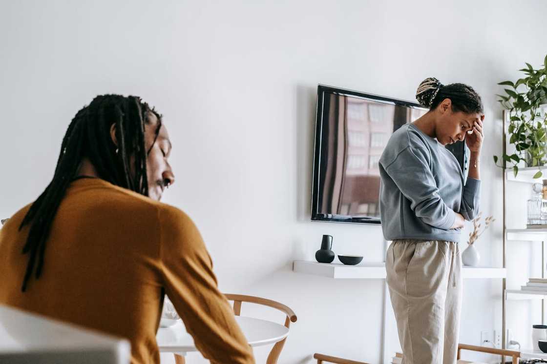Couple standing apart in a living room during a tense conversation.