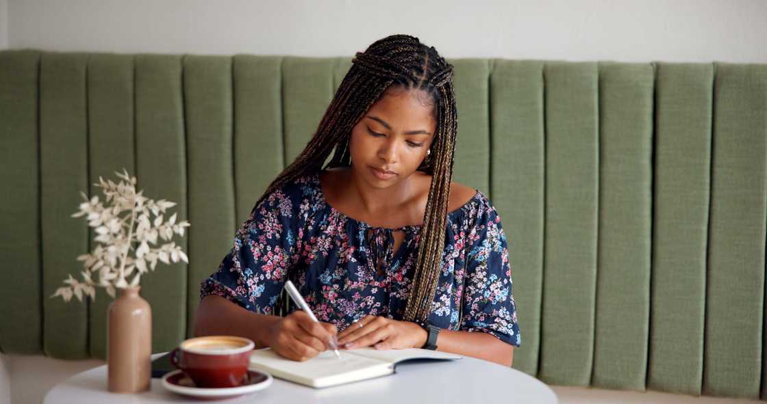 A lady is journaling at a cafe A lady is journaling at a cafe