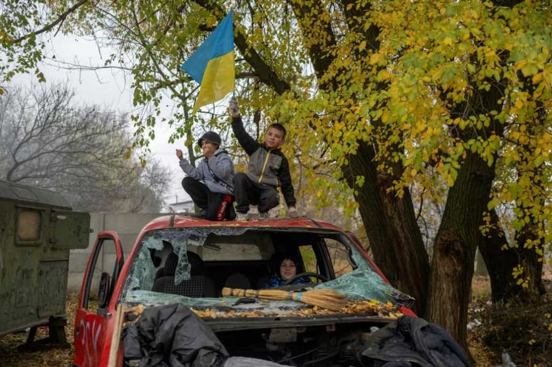 A young boy waves a Ukrainian flag from a destroyed car at a former Russian checkpoint at the entrance to Kherson A young boy waves a Ukrainian flag from a destroyed car at a former Russian checkpoint at the entrance to Kherson