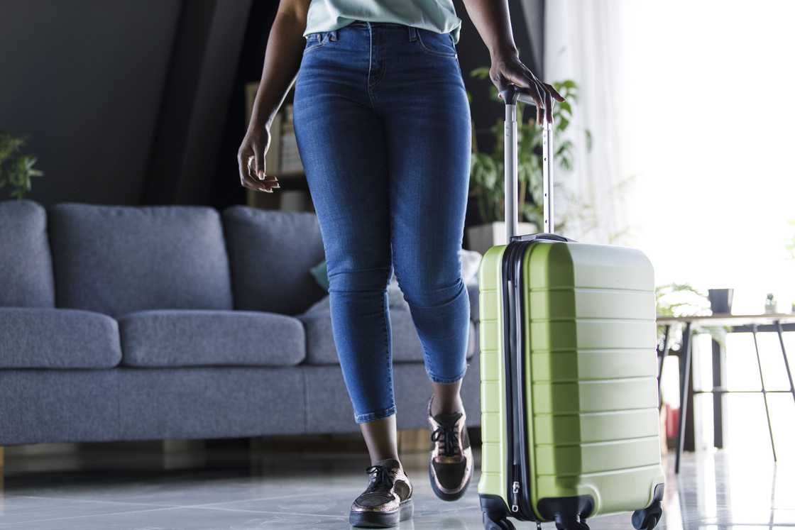 Woman dragging suitcase out of a dimly lit apartment. Woman dragging suitcase out of a dimly lit apartment.