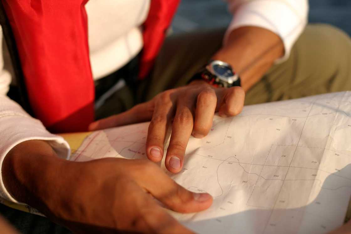 A person pointing at a paper map while planning a route outdoors. A person pointing at a paper map while planning a route outdoors.