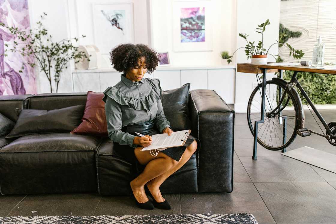 A woman sitting on leather sofa while signing documents
