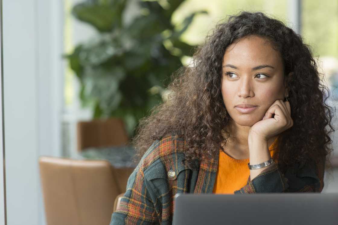 A young woman thinking while looking out the window of a cafe