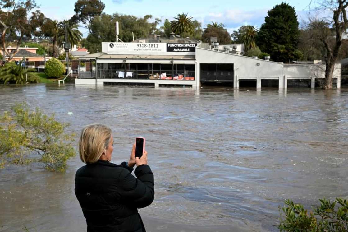 A woman films a flooded area in the Maribyrnong suburb of Melbourne on Friday A woman films a flooded area in the Maribyrnong suburb of Melbourne on Friday