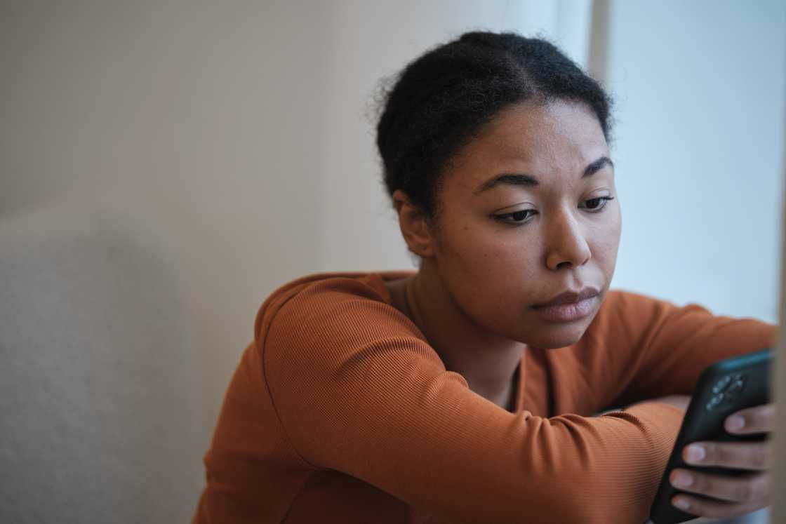 A woman sadly looking at her phone. A woman sadly looking at her phone.