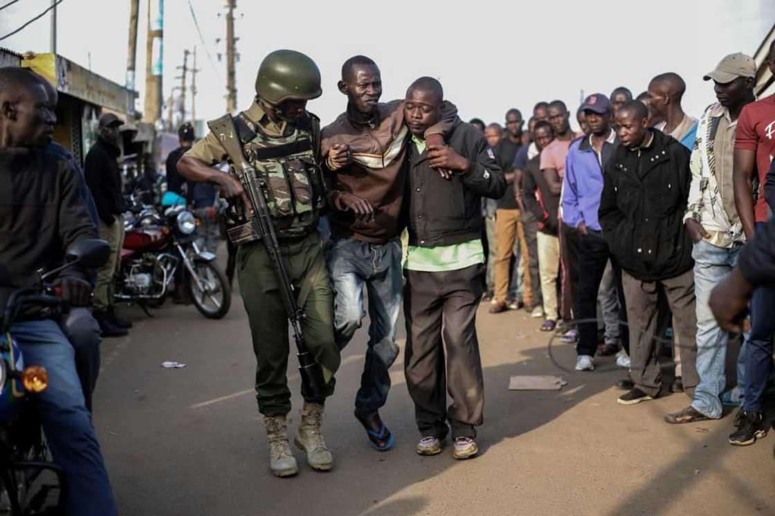 A Kenyan police officer helps disabled voter at a polling station in the lakeside city of Kisumu