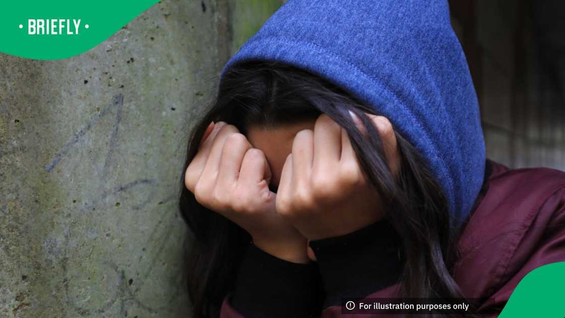 A teenage girl with her head in her hands showing signs of mental health issues