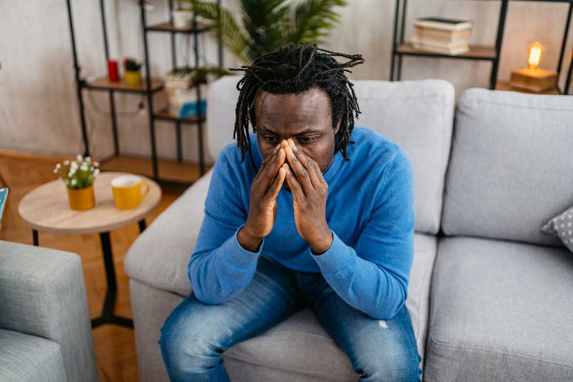 A close-up of tired hands wiping tears in a dimly lit room. A close-up of tired hands wiping tears in a dimly lit room.