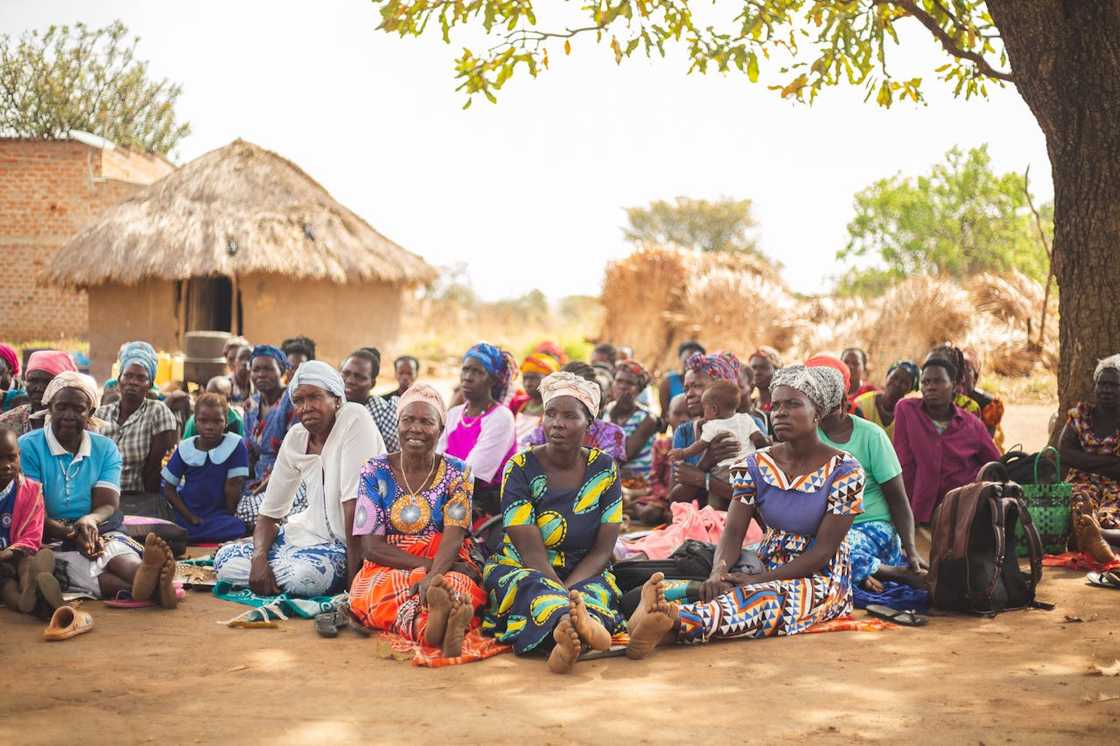 Rural women seated outdoors during a community gathering.
