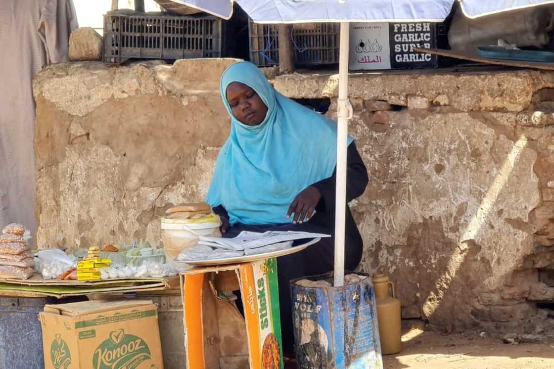 A woman sells foodstuffs at a stall in a Khartoum street as she tries to make a living amid the near-daily air strikes and artillery bombardments