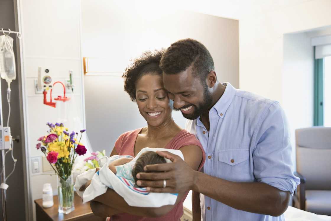 A couple holds their baby in their arms.