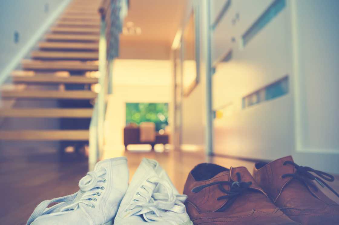 Two pairs of shoes by a staircase in a modern home. Two pairs of shoes by a staircase in a modern home.
