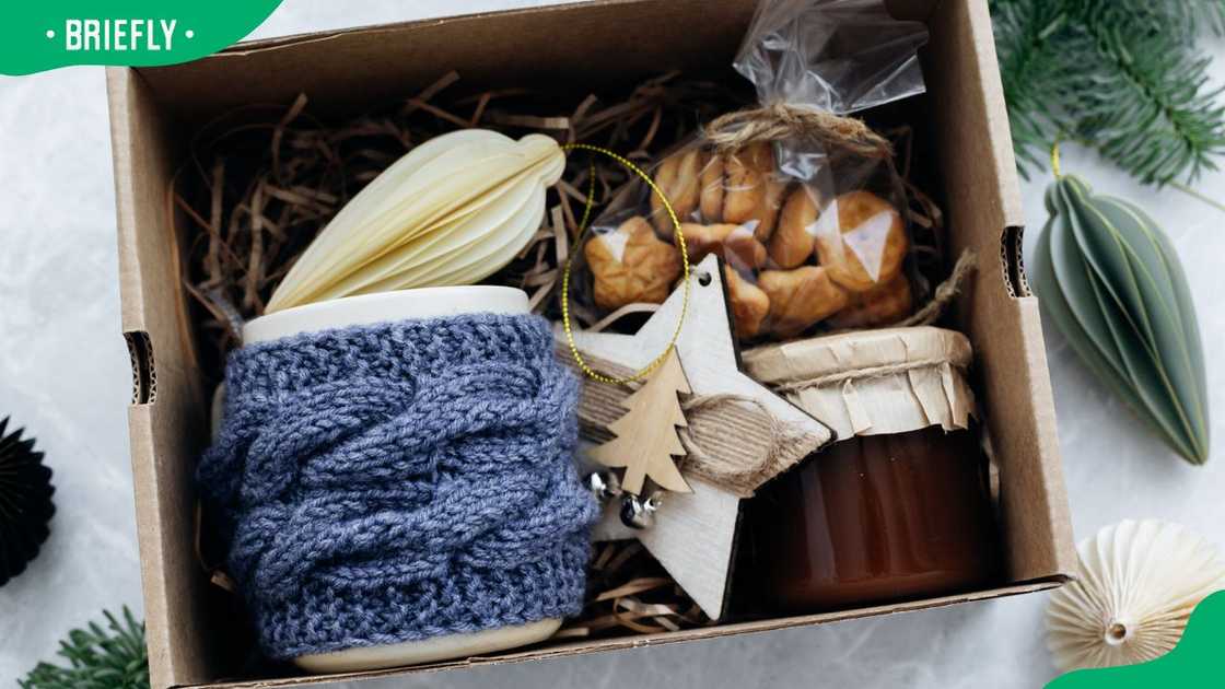 A Christmas gift basket with cookies and decorations in a cardboard box