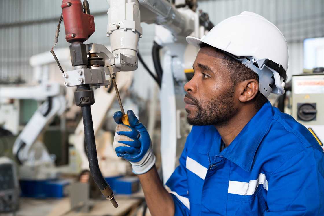 A male technician worker maintaining parts of the machine. A male technician worker maintaining parts of the machine.