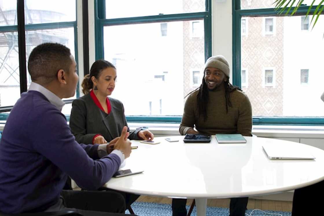 A group of people sitting around a white table A group of people sitting around a white table