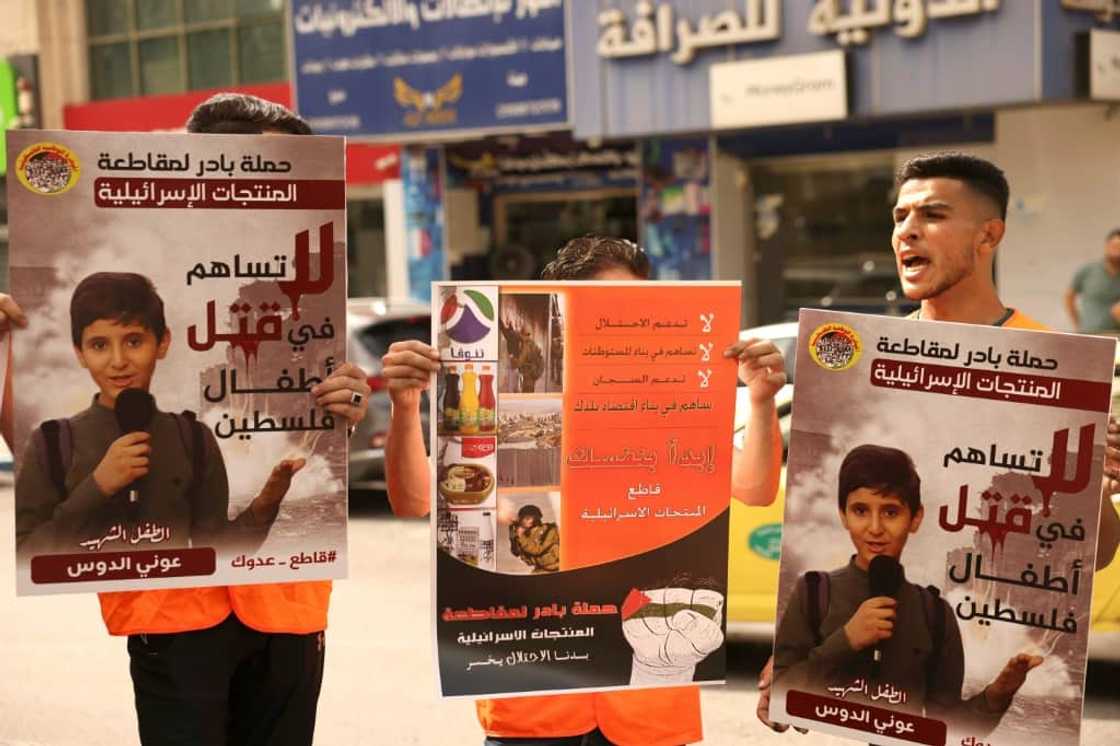 Palestinians hold posters demanding a boycott of Israeli products during a rally in the occupied West Bank city of Hebron Palestinians hold posters demanding a boycott of Israeli products during a rally in the occupied West Bank city of Hebron