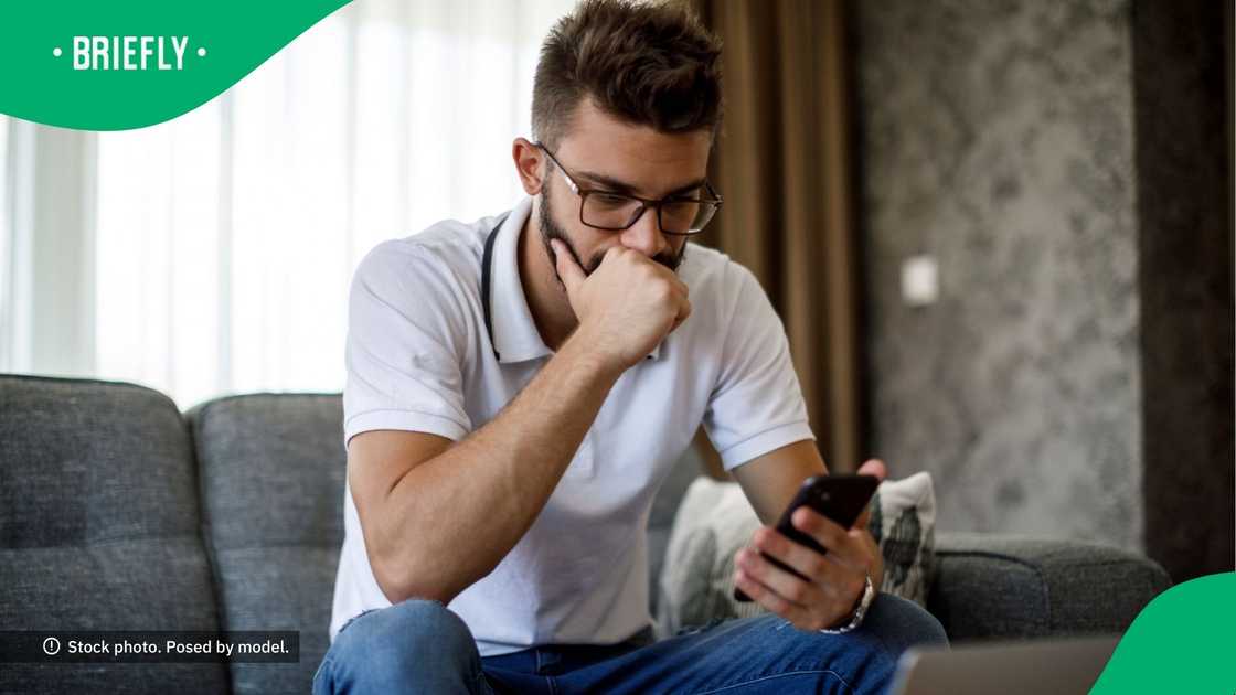 A confused man looking at his phone. A confused man looking at his phone.