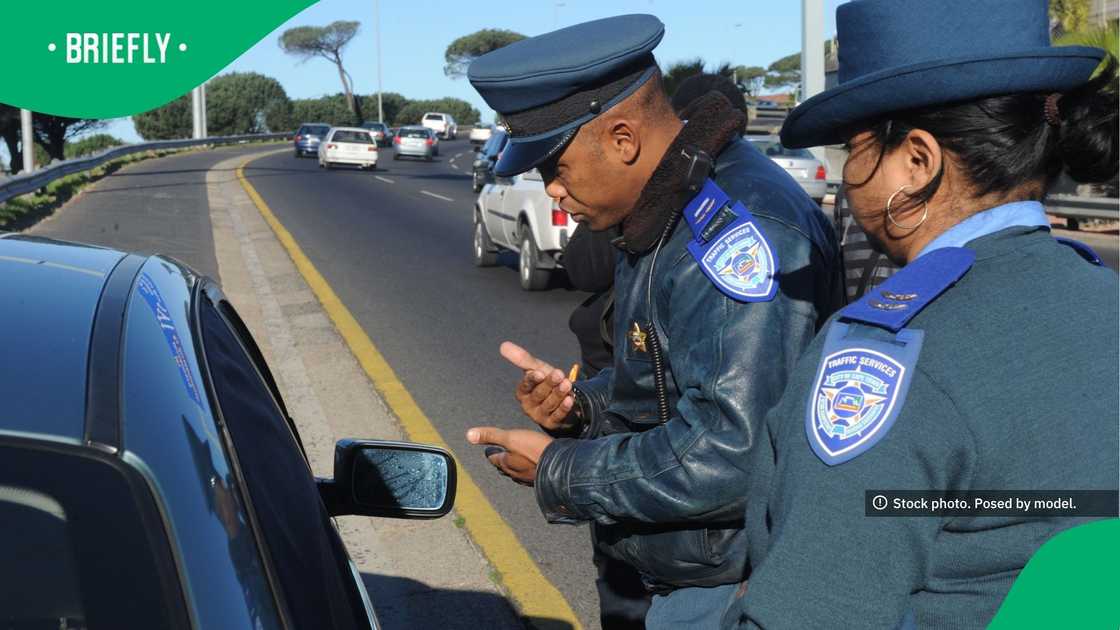 Wearing their official blue uniforms and caps, the traffic enforcers conducted a vehicle check next to an active flow of highway traffic Wearing their official blue uniforms and caps, the traffic enforcers conducted a vehicle check next to an active flow of highway traffic