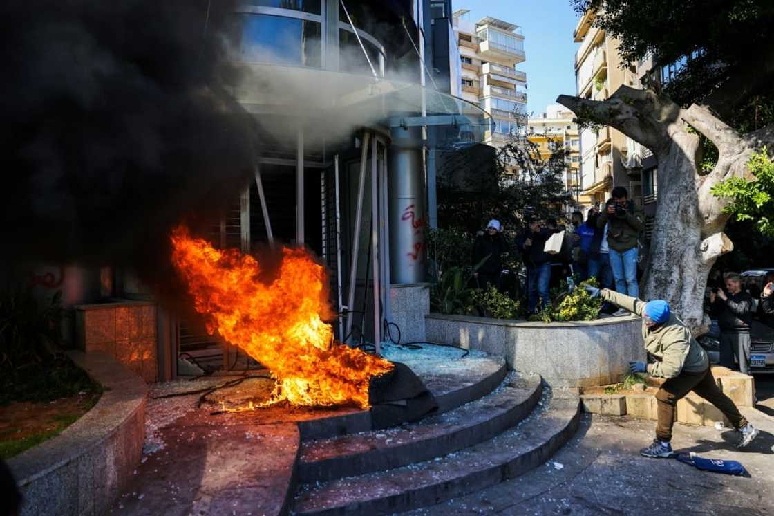 A protester throws a brick at a bank after setting fire to tyres during a demonstration in Beirut A protester throws a brick at a bank after setting fire to tyres during a demonstration in Beirut
