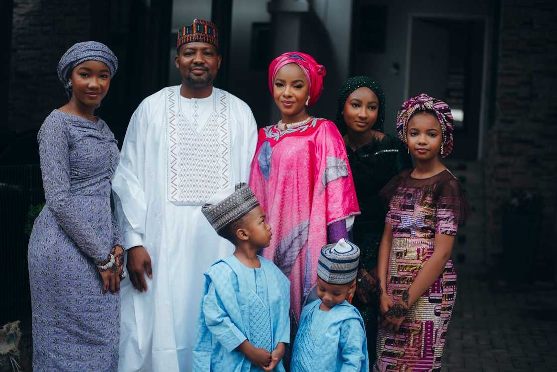 A family dressed in traditional attire poses together outdoors.