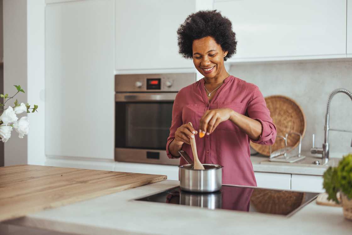 A smiling woman stirring a pot