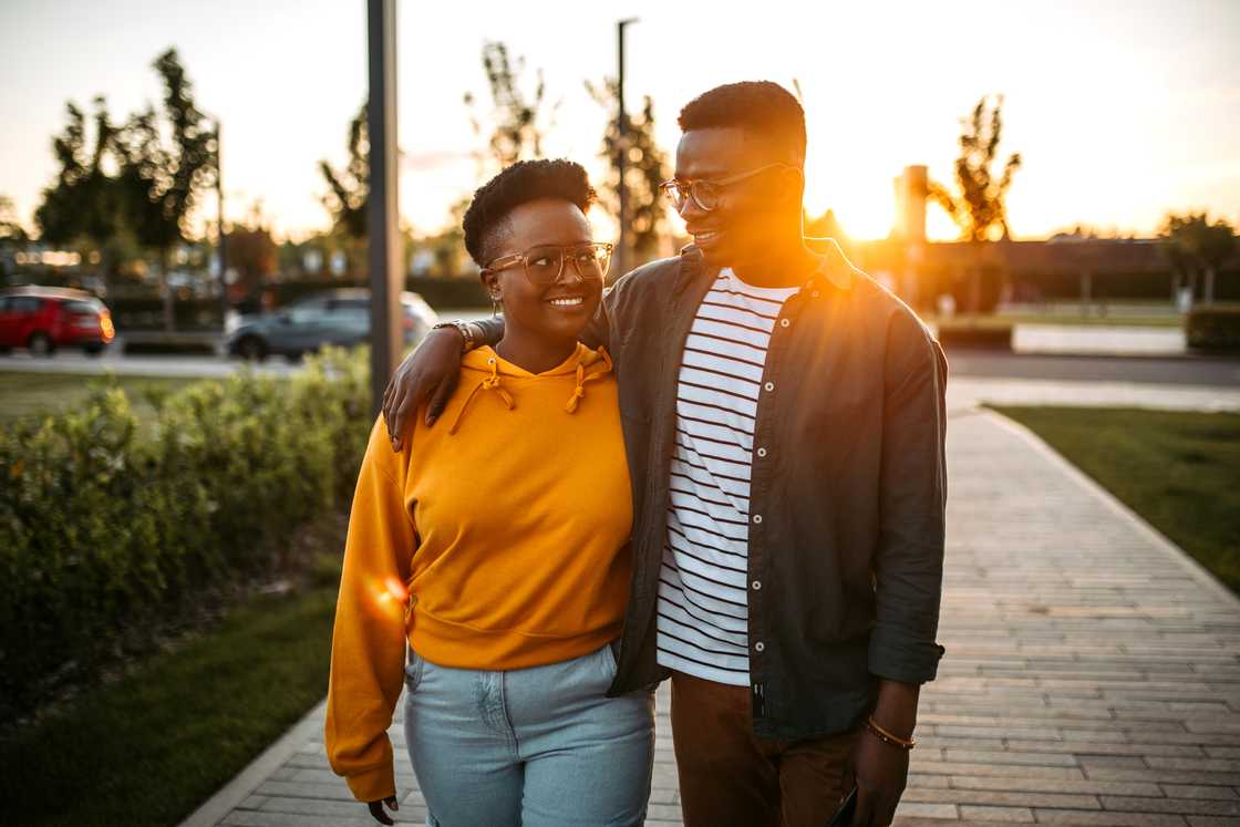 Two people walk together at sunset, one with an arm around the other. Two people walk together at sunset, one with an arm around the other.