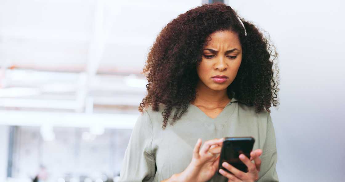 A woman angrily typing on her phone. A woman angrily typing on her phone.