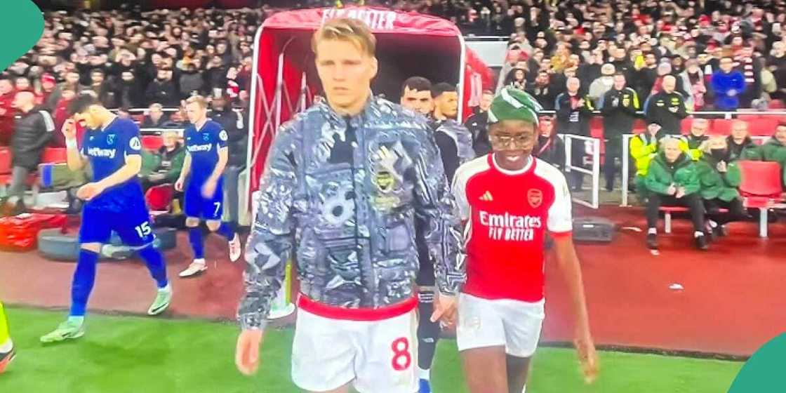 Boy walks into pitch with Martn Odegaard.