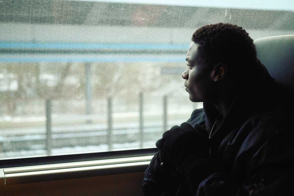 Person in dark clothing looks out a train window at snowy tracks. Person in dark clothing looks out a train window at snowy tracks.