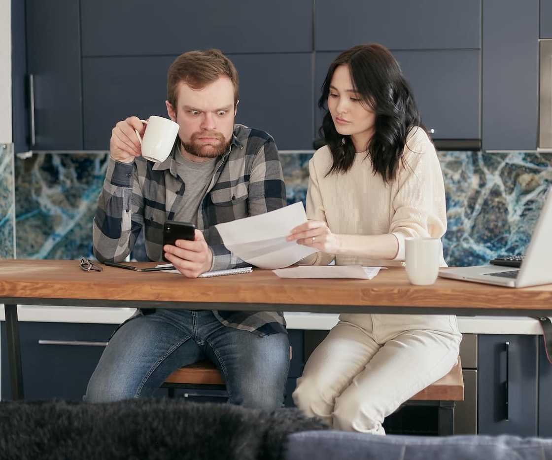A man looking at a piece of paper held by a woman. A man looking at a piece of paper held by a woman.