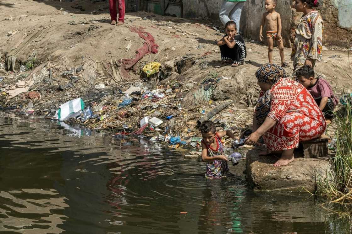 A child helps a woman wash pots in the Nile near Giza in Egypt